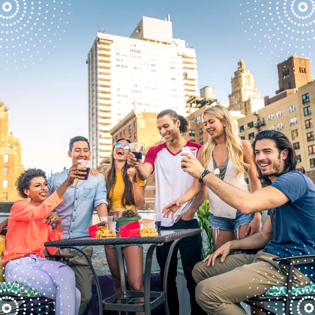 A person smiling and raising a glass of champagne with friends at a rooftop bar overlooking a city. Guide to Money After Divorce