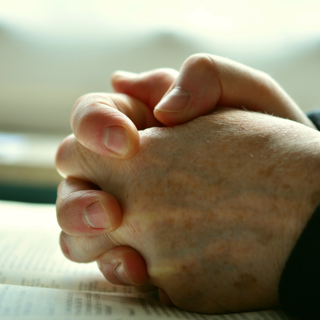 Hands in prayer on divorce paperwork symbolizing emotional struggle